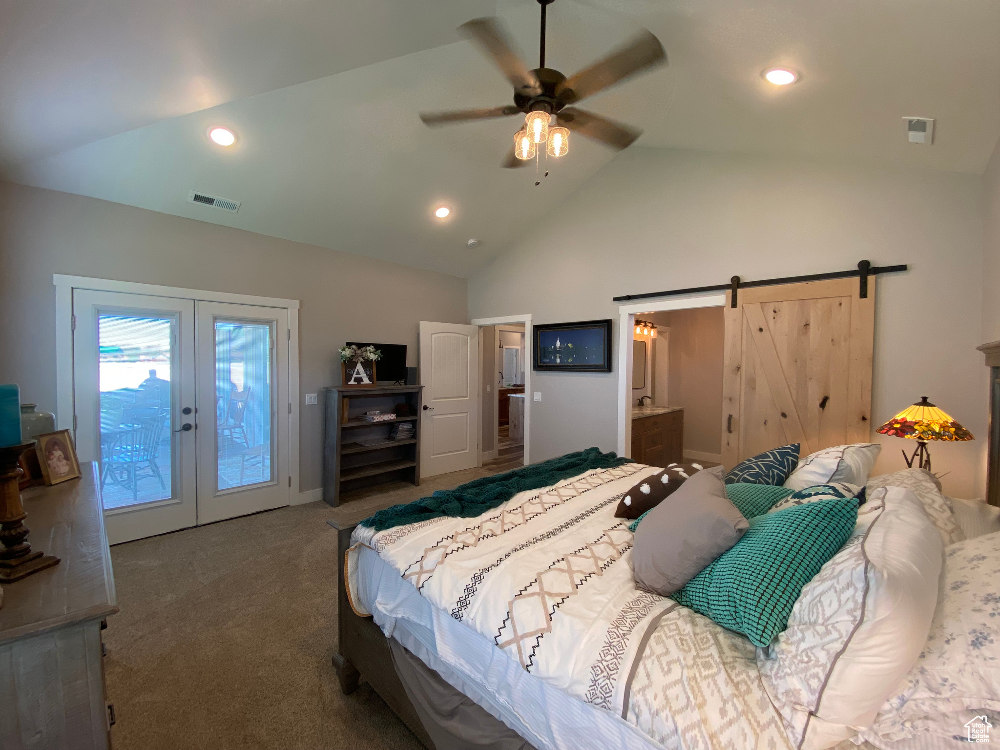 Bedroom featuring connected bathroom, access to exterior, carpet floors, a barn door, and ceiling fan