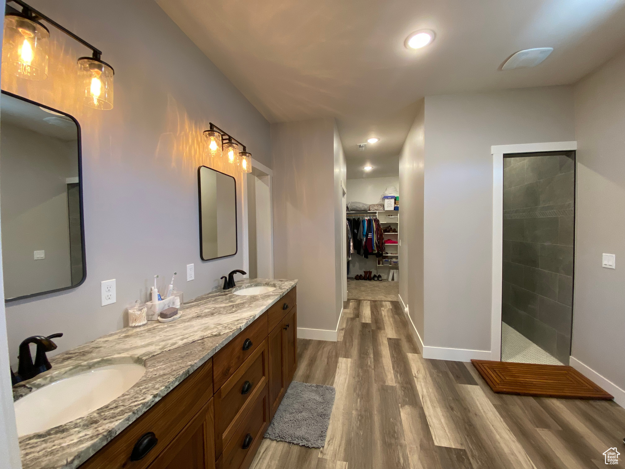 Bathroom featuring a tile shower, dual sinks, hardwood / wood-style floors, and large vanity