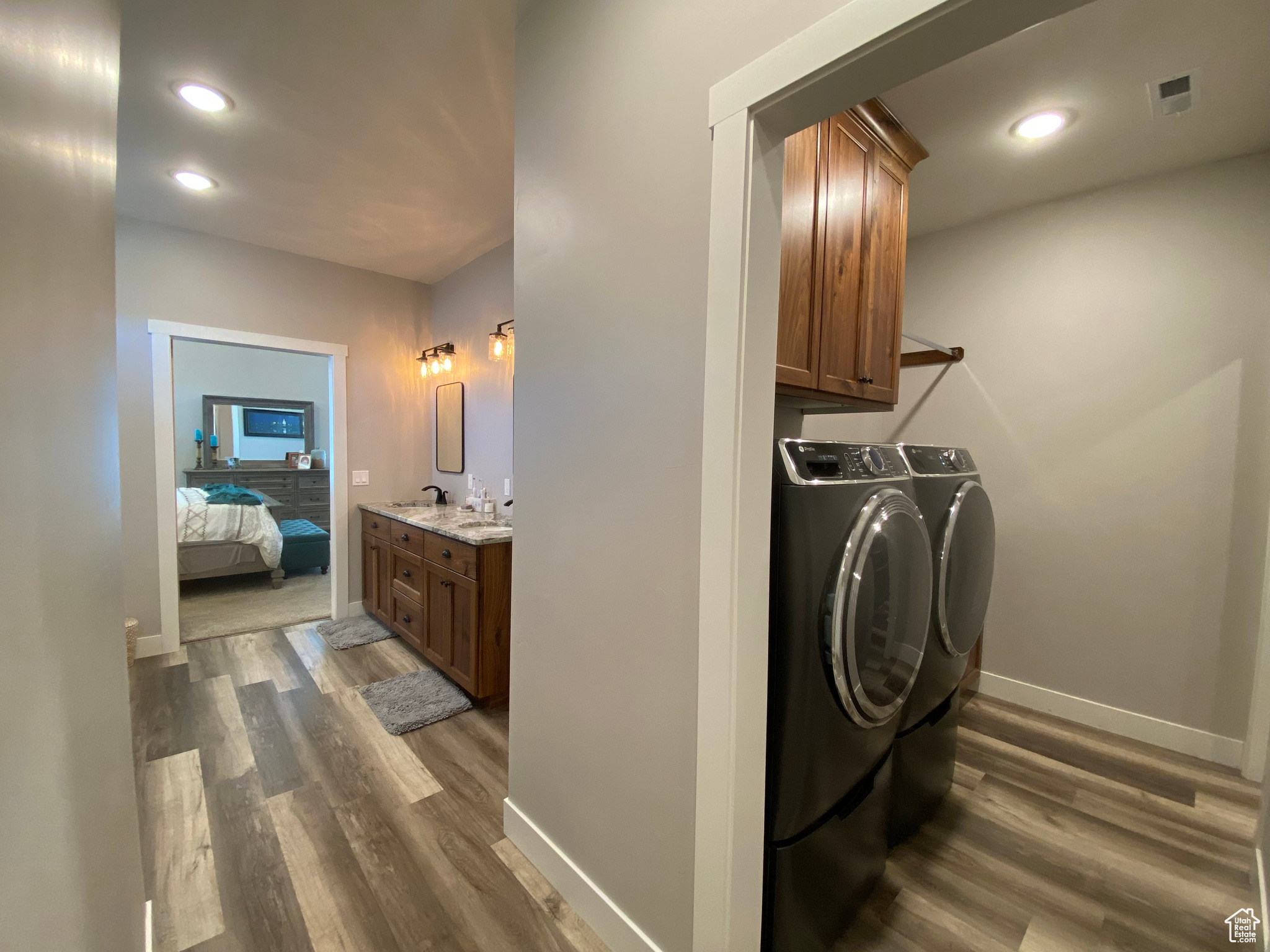 Clothes washing area featuring cabinets, sink, dark hardwood / wood-style floors, and washing machine and clothes dryer