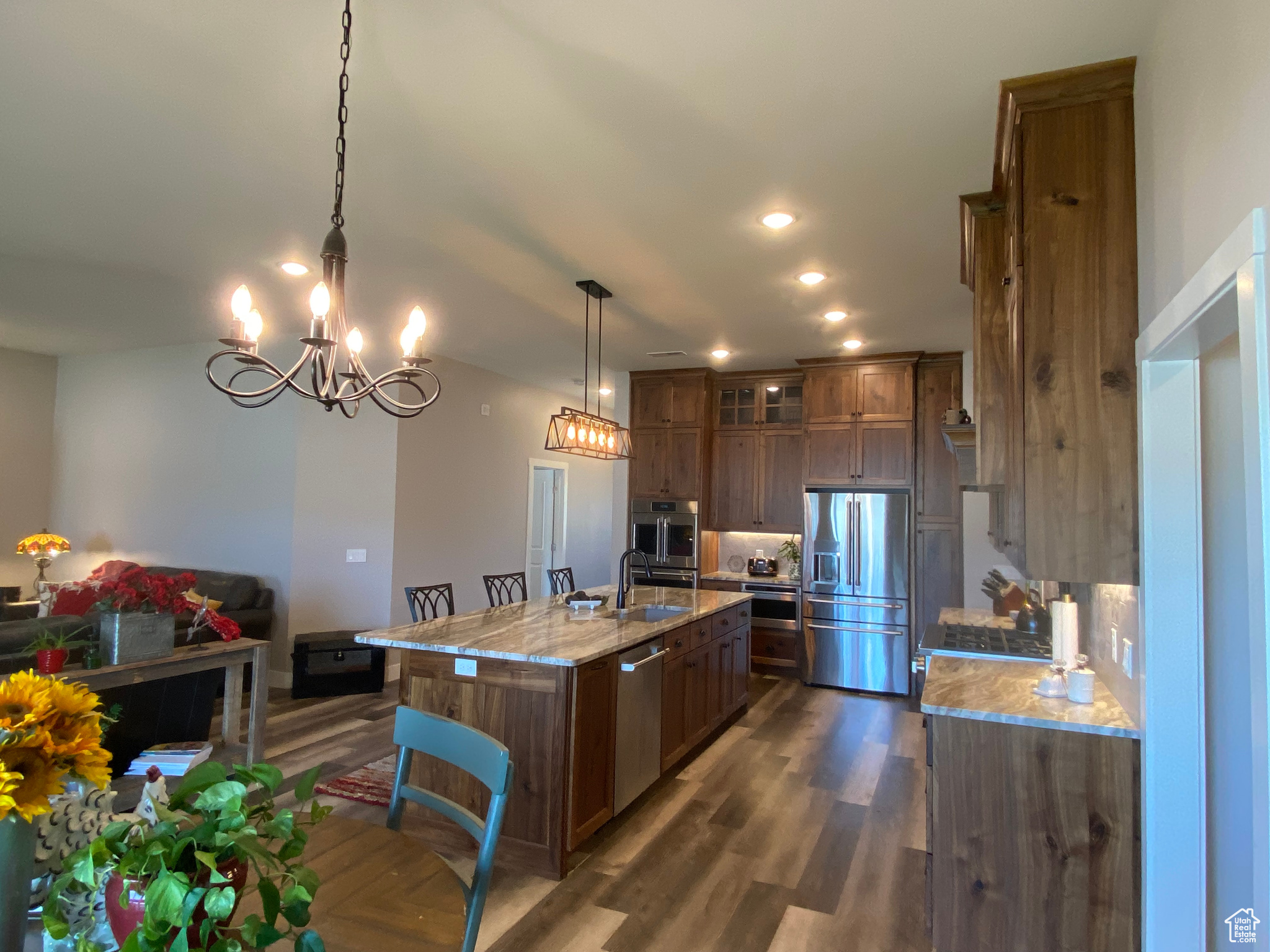 Kitchen featuring dark hardwood / wood-style floors, pendant lighting, light stone counters, sink, and appliances with stainless steel finishes