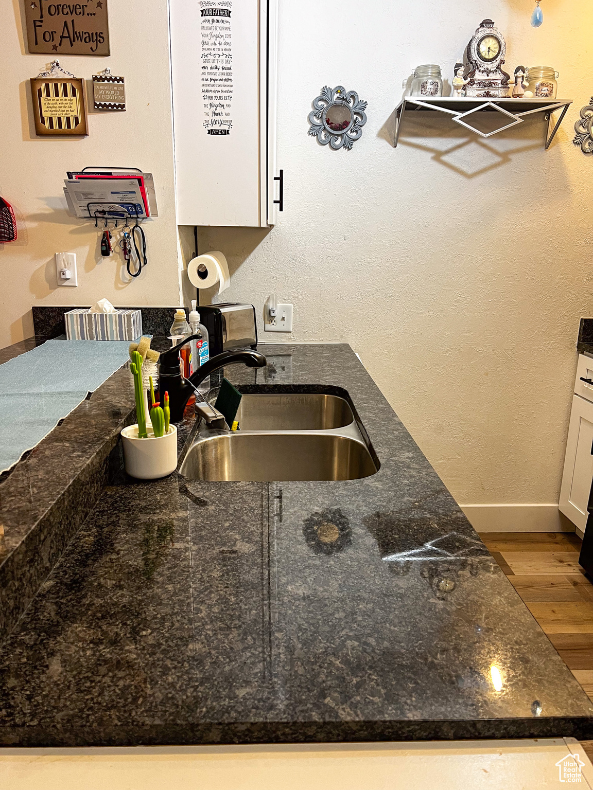 Kitchen with sink, white cabinetry, light hardwood / wood-style floors, and dark stone counters