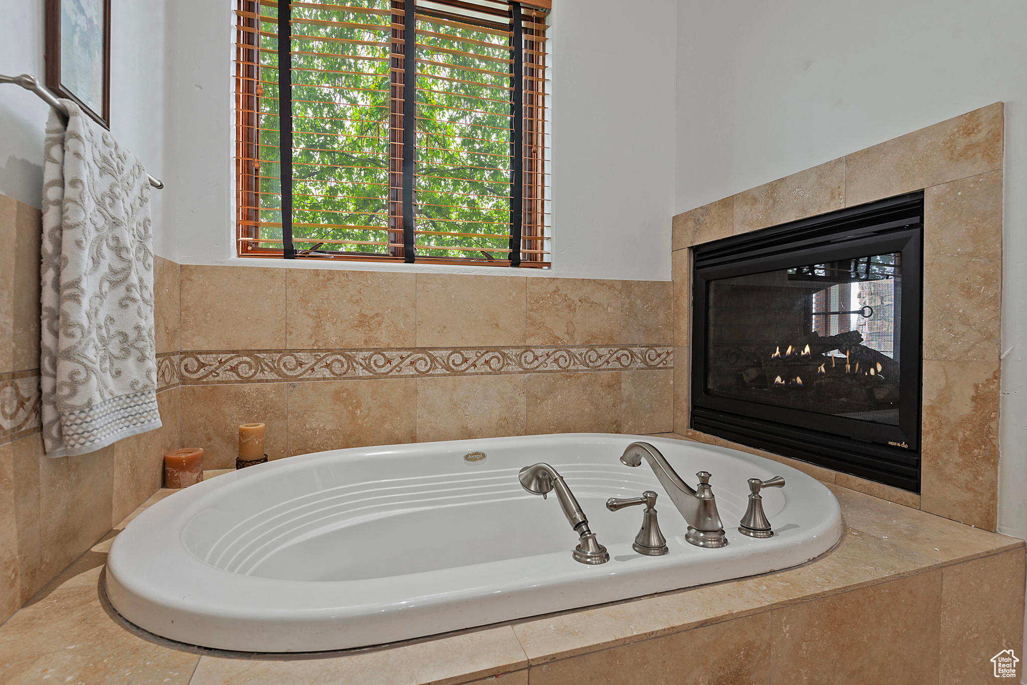 Bathroom featuring a multi sided fireplace and tiled tub