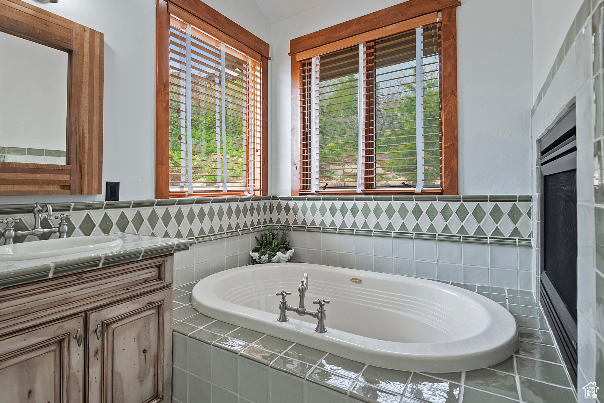 Bathroom featuring tiled tub and large vanity with lots of natural sunlight