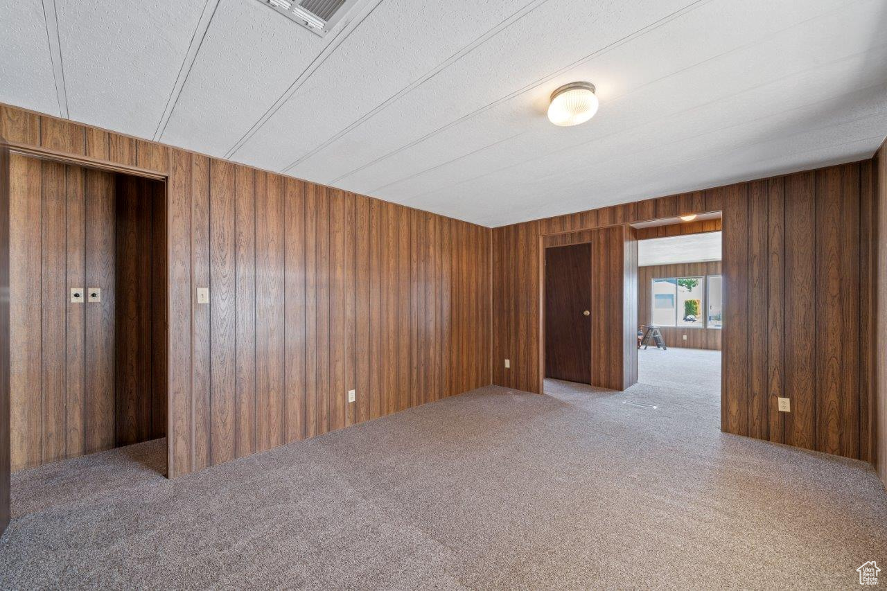 Carpeted spare room with a textured ceiling and wood walls