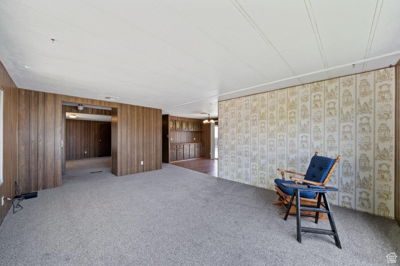 Unfurnished room featuring wooden walls and carpet floors