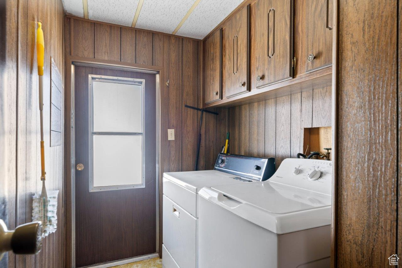 Clothes washing area featuring cabinets, separate washer and dryer, hookup for a washing machine, and wood walls