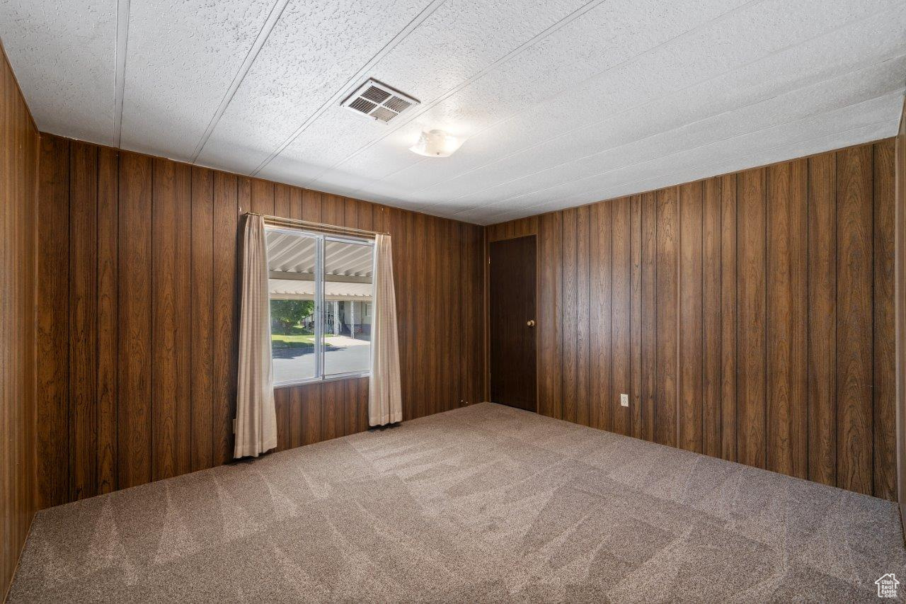 Unfurnished room featuring wooden walls and carpet flooring