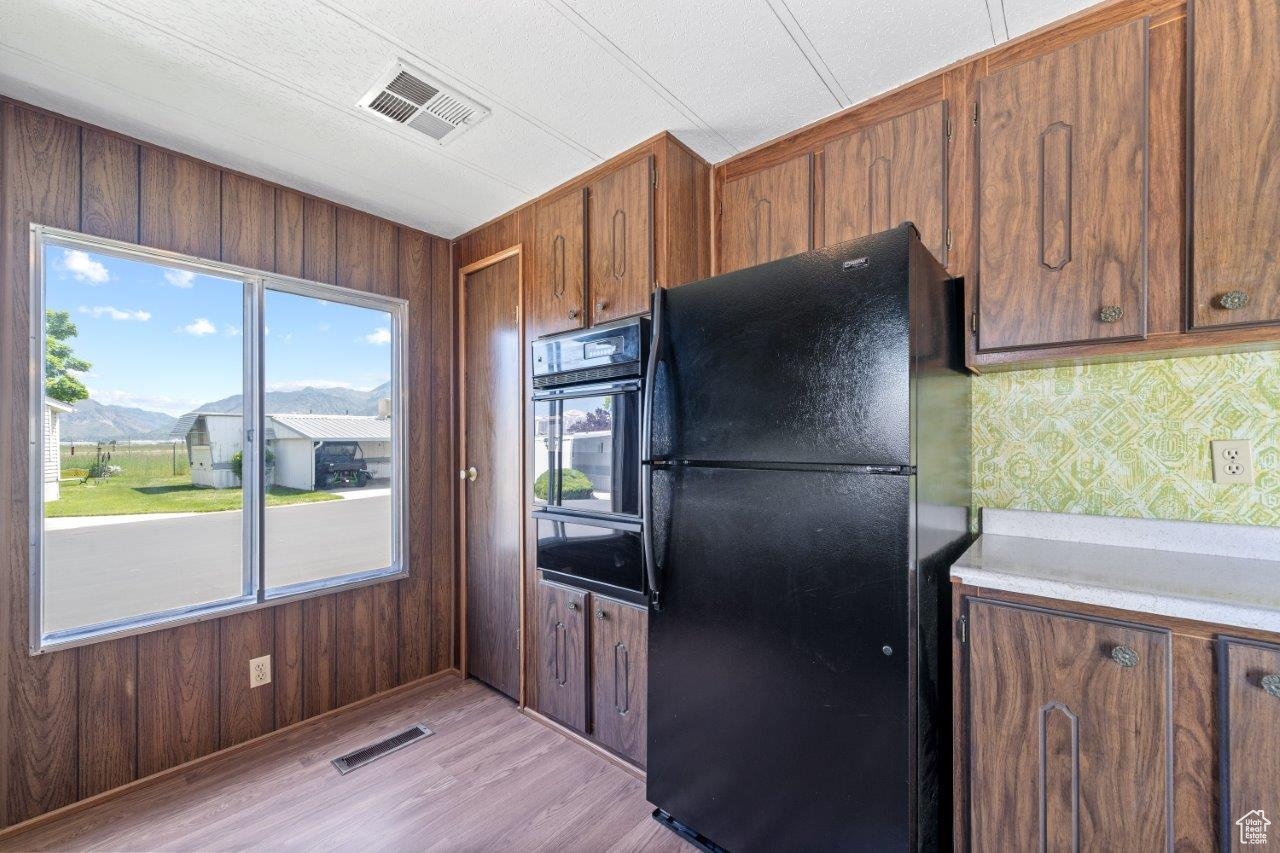 Kitchen with wooden walls, light hardwood / wood-style floors, and black appliances