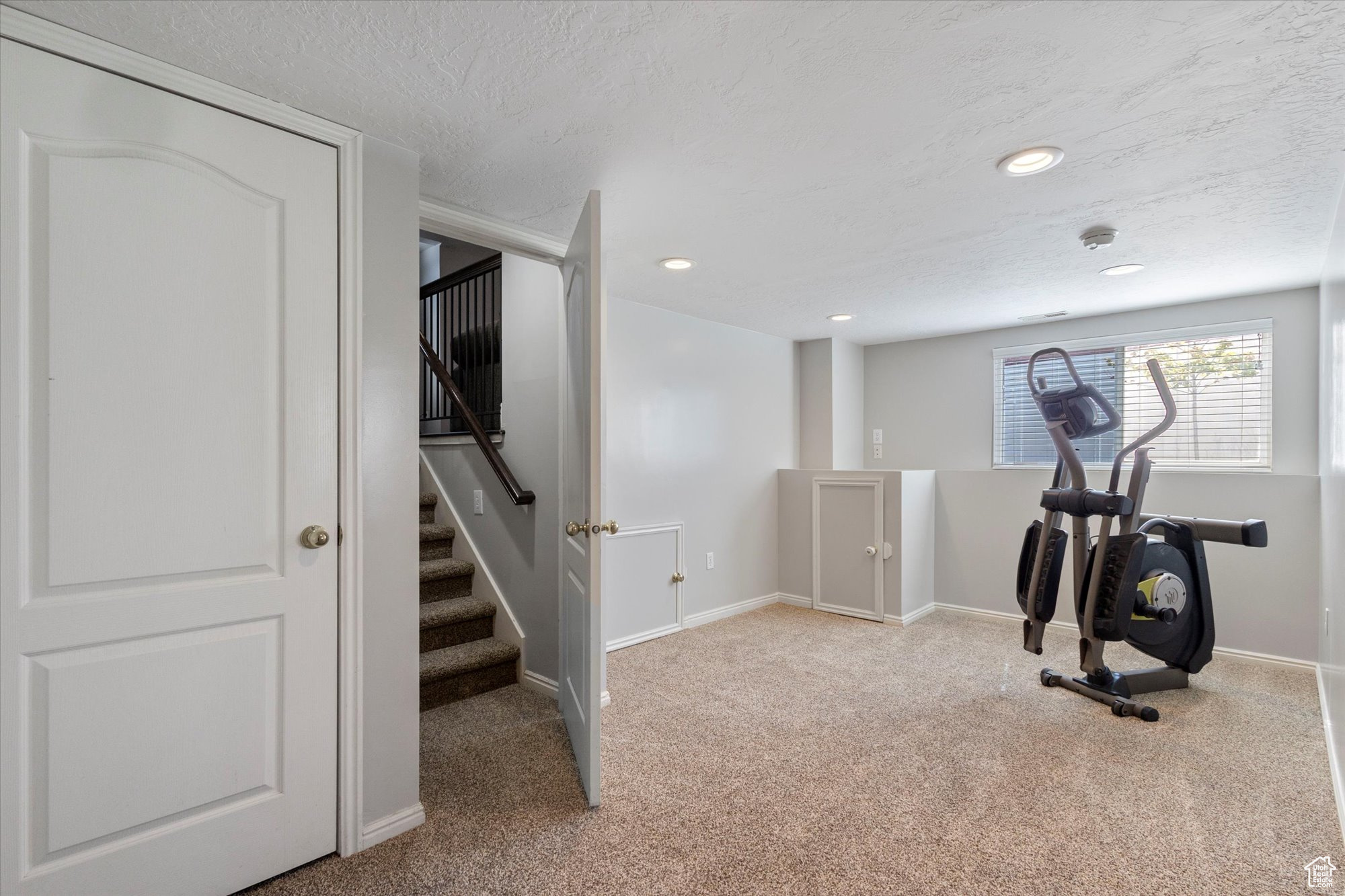 Workout area featuring a textured ceiling and light colored carpet