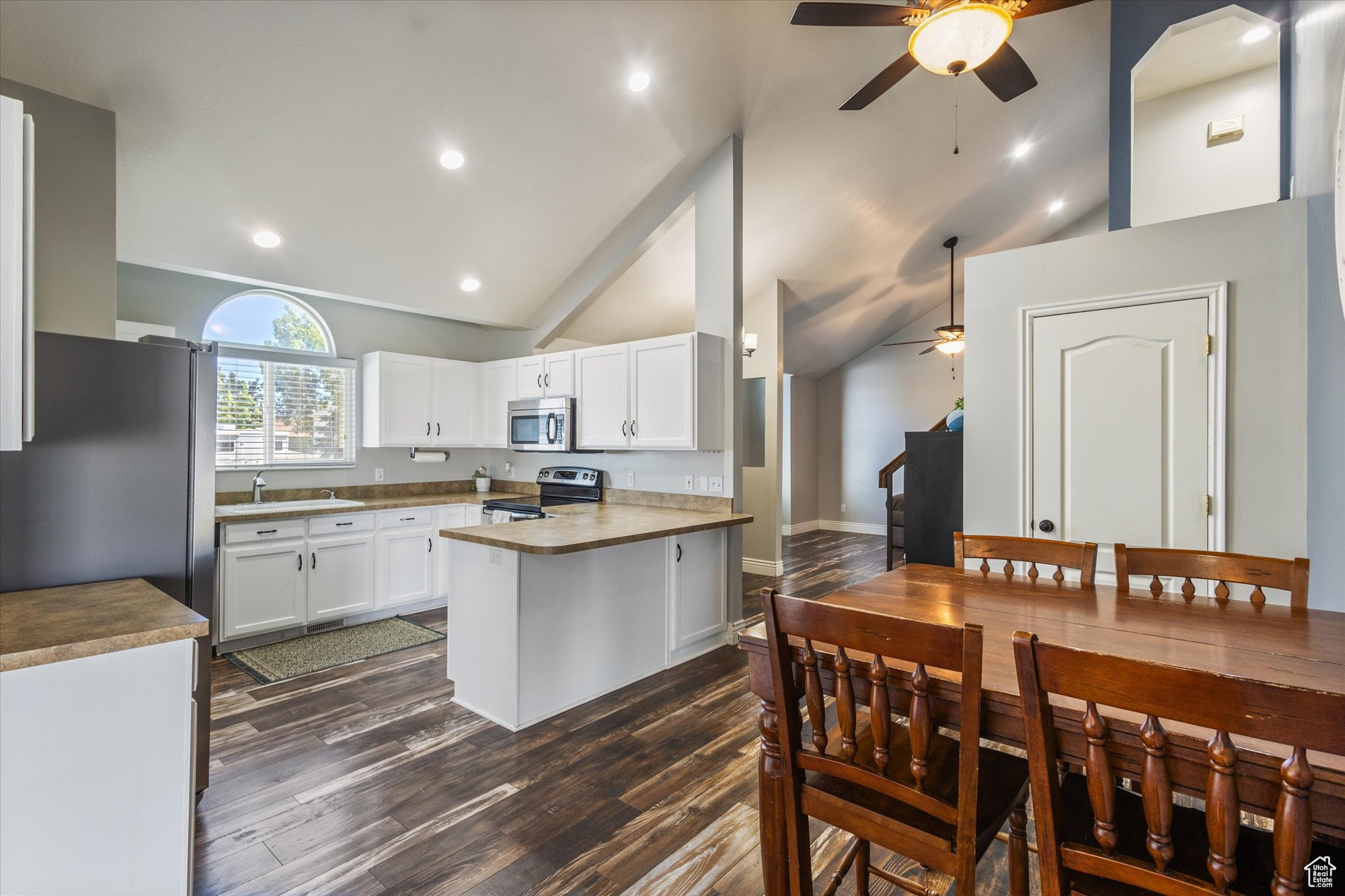 Kitchen with white cabinets, appliances with stainless steel finishes, dark hardwood / wood-style flooring, and ceiling fan