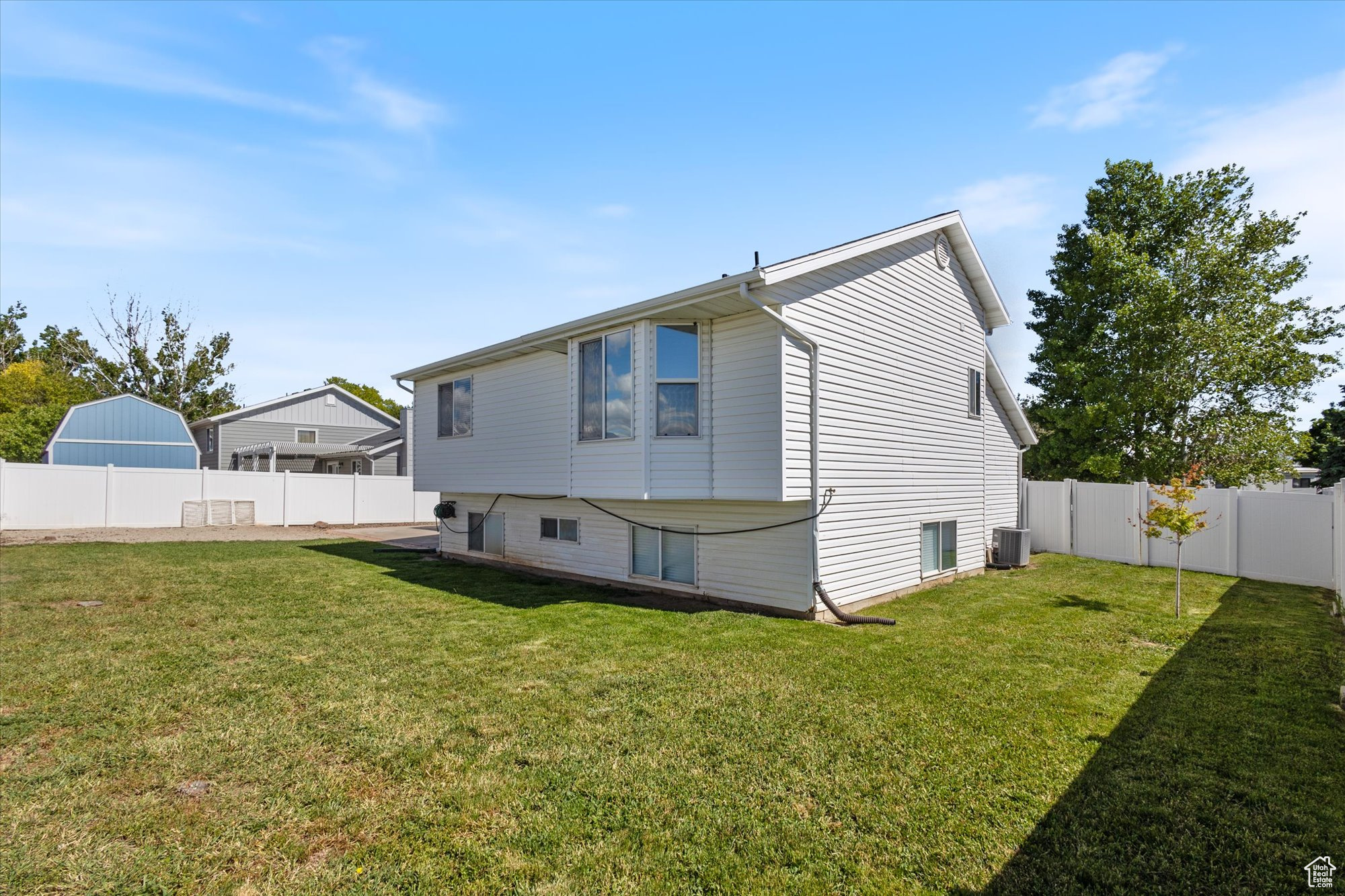 Rear view of house with central air condition unit and a lawn