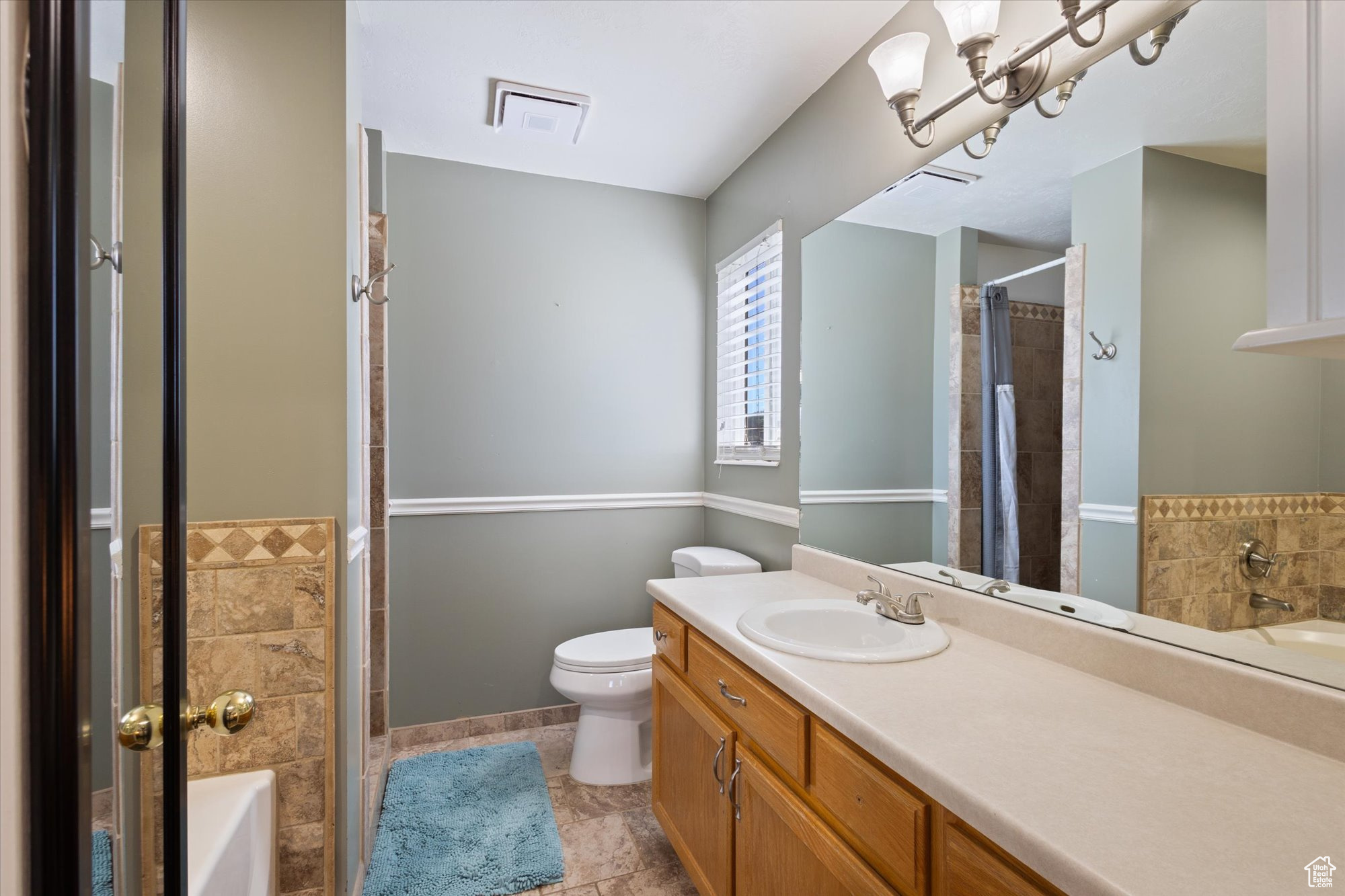 Full bathroom featuring shower / bath combination with curtain, vanity, toilet, and tile floors