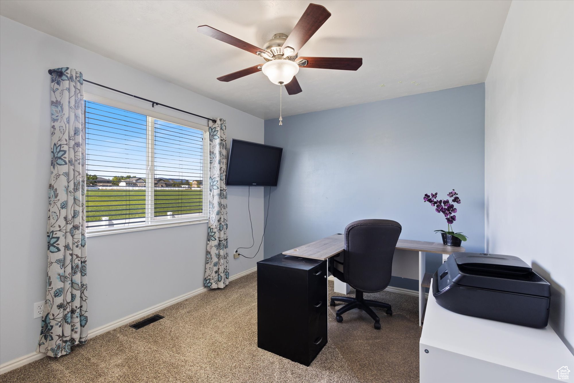 Carpeted home office featuring ceiling fan