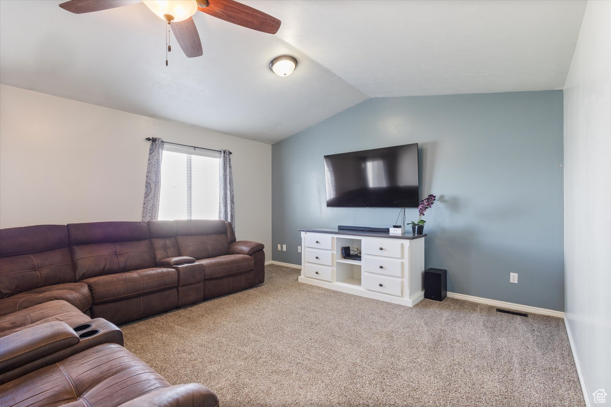 Living room featuring light colored carpet, vaulted ceiling, and ceiling fan