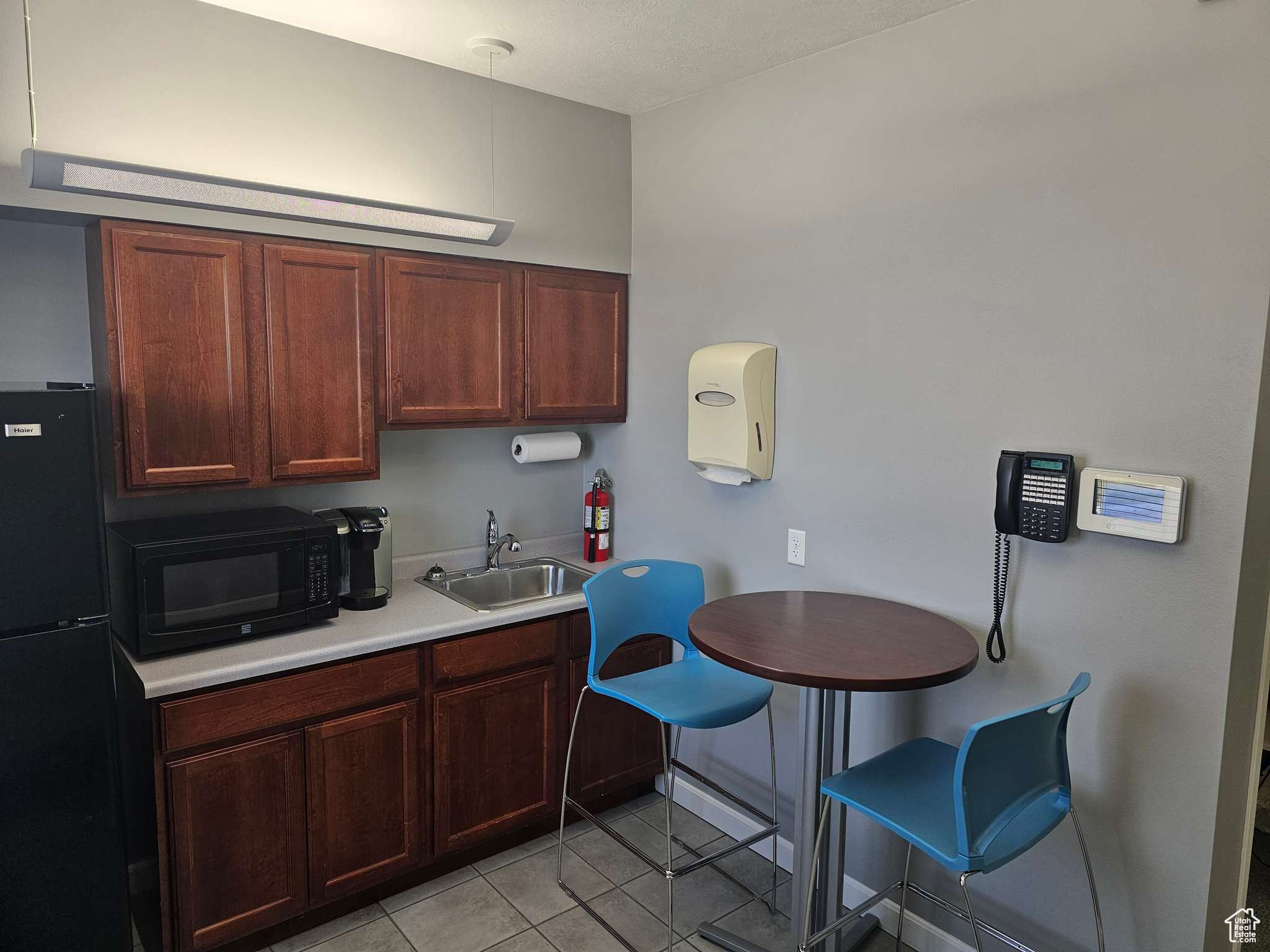 Kitchen with sink, black appliances, and light tile floors