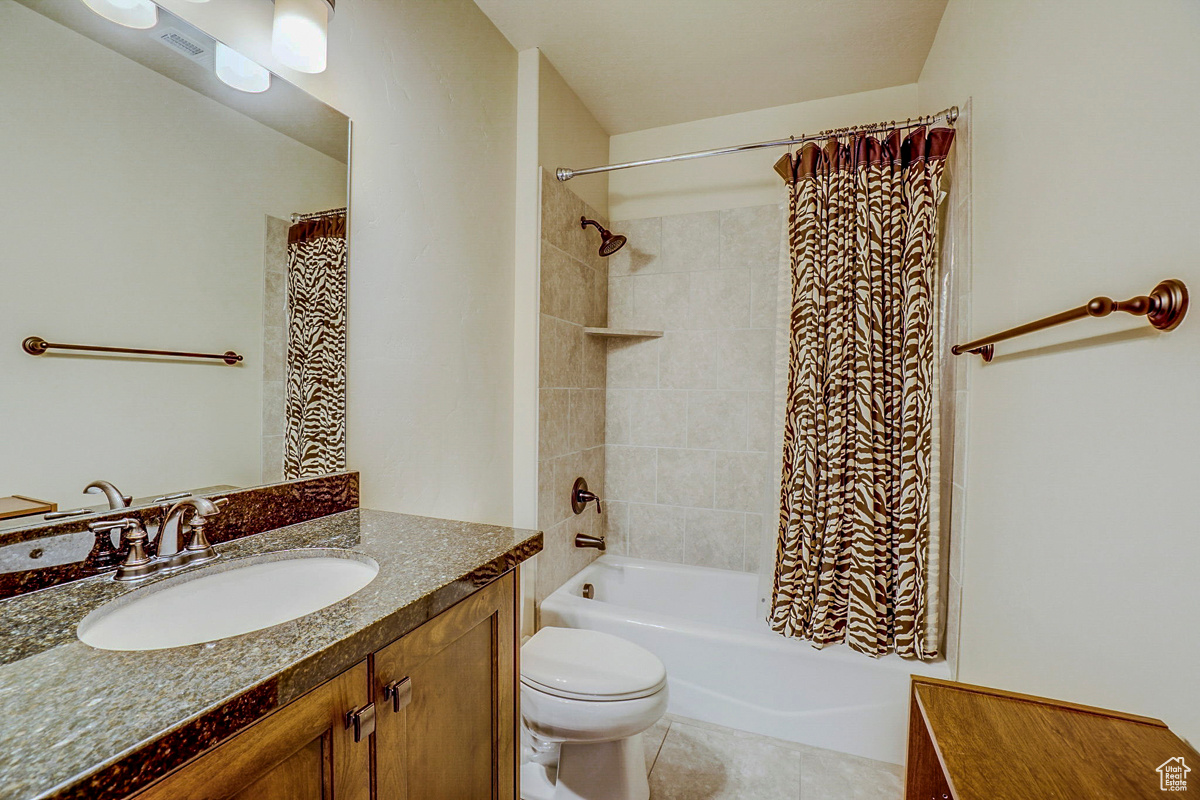 Full bathroom featuring tile flooring, vanity, toilet, and shower / bath combo with shower curtain