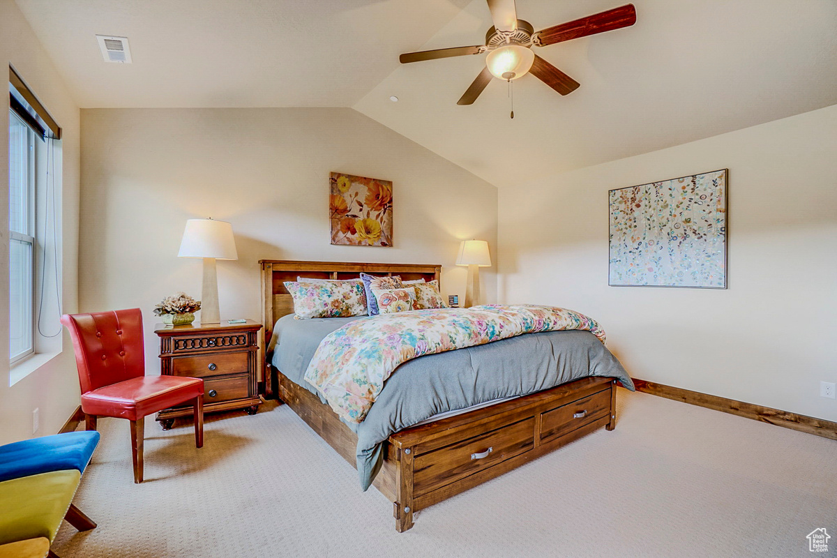 Carpeted bedroom featuring ceiling fan and lofted ceiling