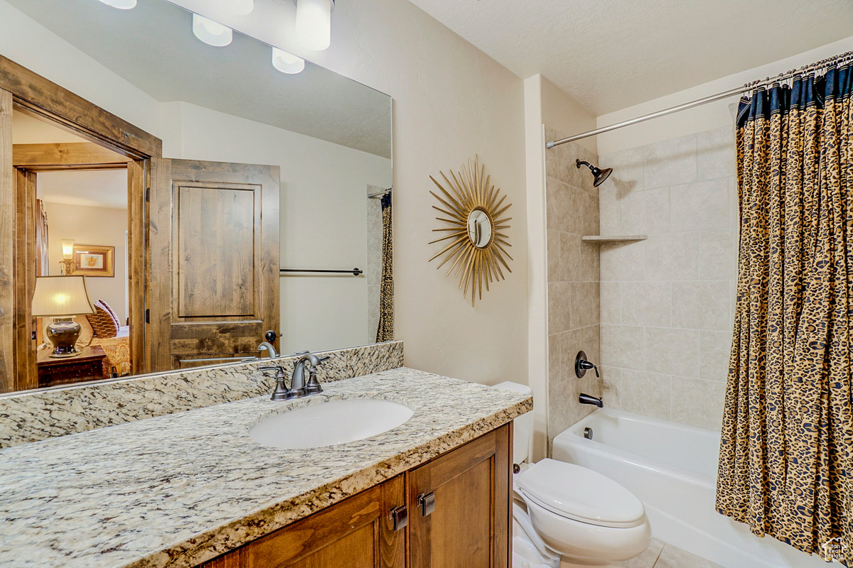 Full bathroom featuring tile floors, shower / bath combo with shower curtain, toilet, and vanity