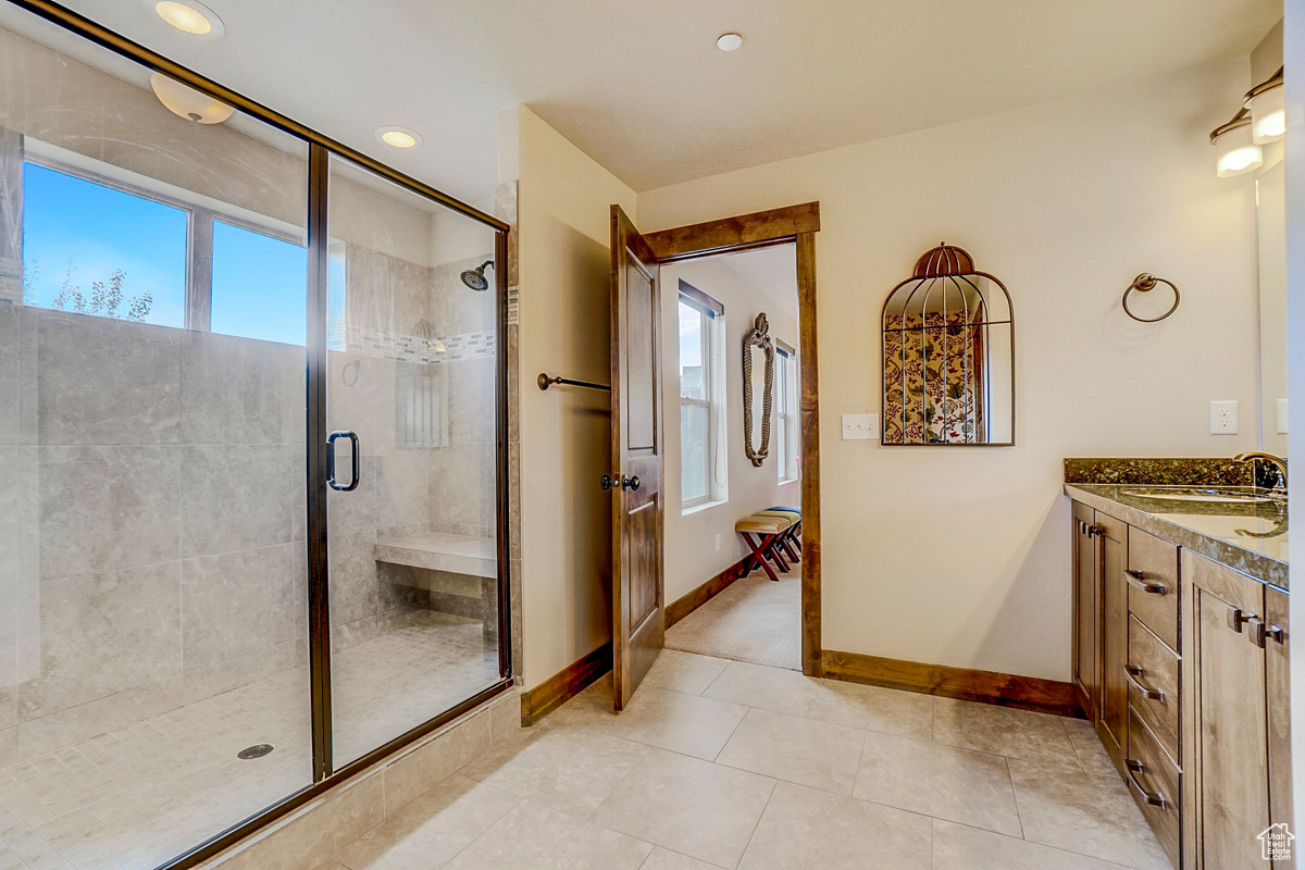 Bathroom featuring a shower with shower door, plenty of natural light, vanity, and tile floors