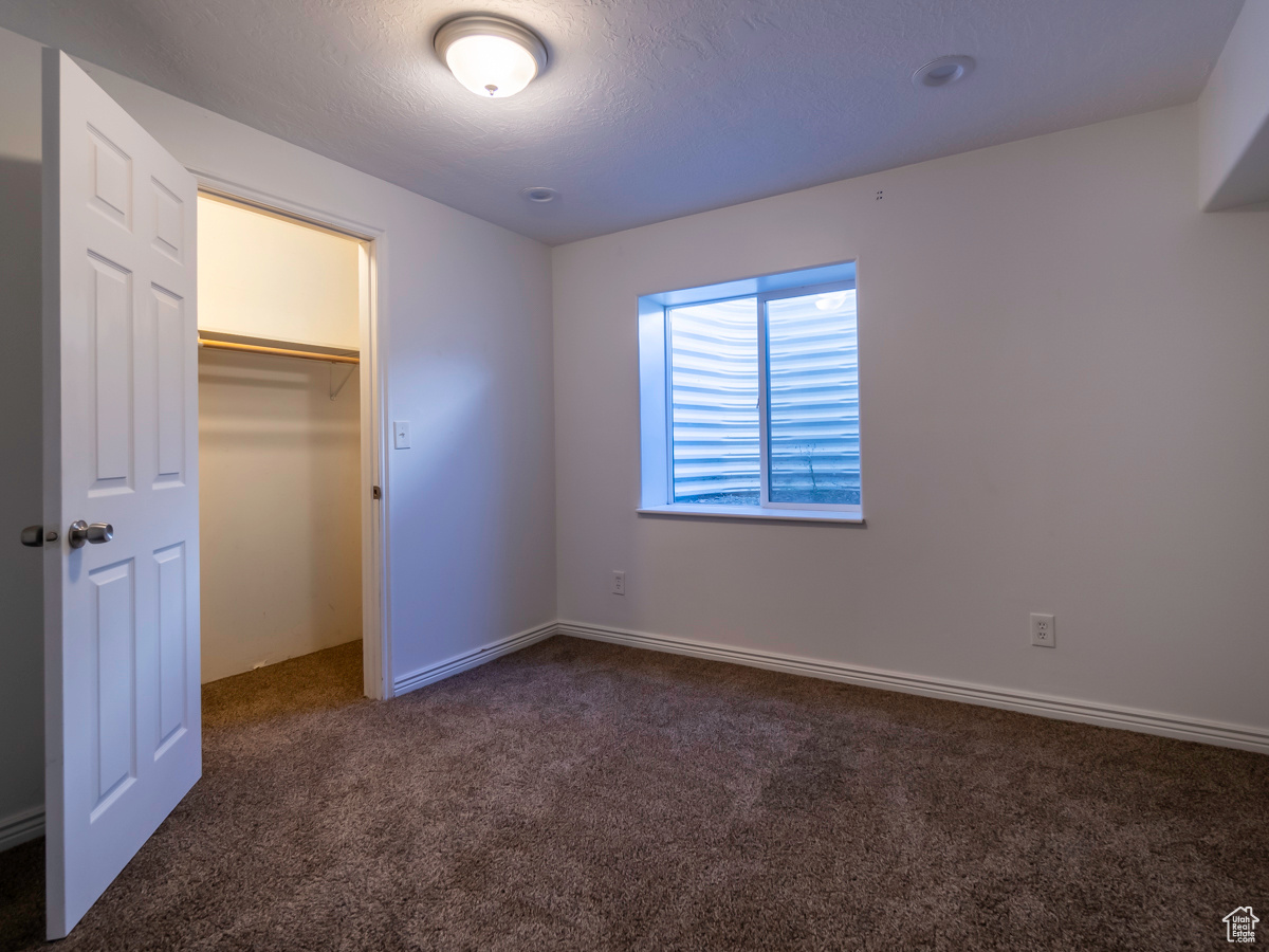 Unfurnished bedroom with dark carpet, a closet, and a spacious closet