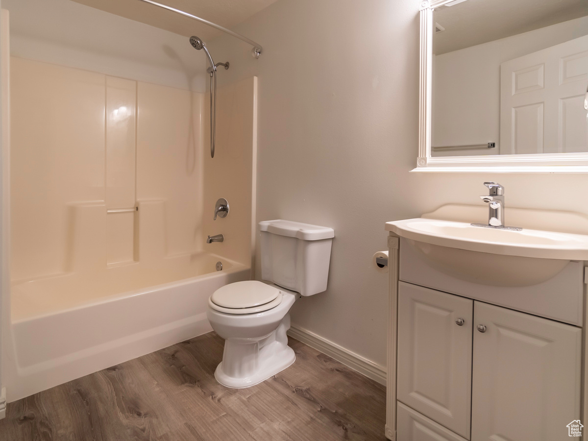 Full bathroom with washtub / shower combination, hardwood / wood-style flooring, toilet, and vanity