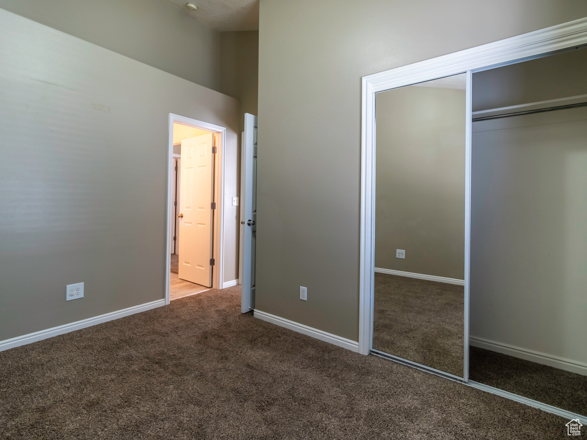 Unfurnished bedroom featuring a high ceiling, a closet, and carpet flooring