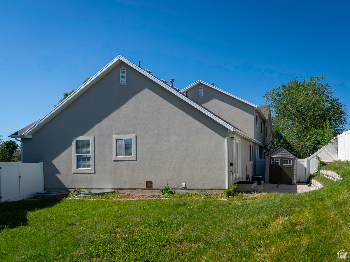 View of side of property with a storage unit and a lawn