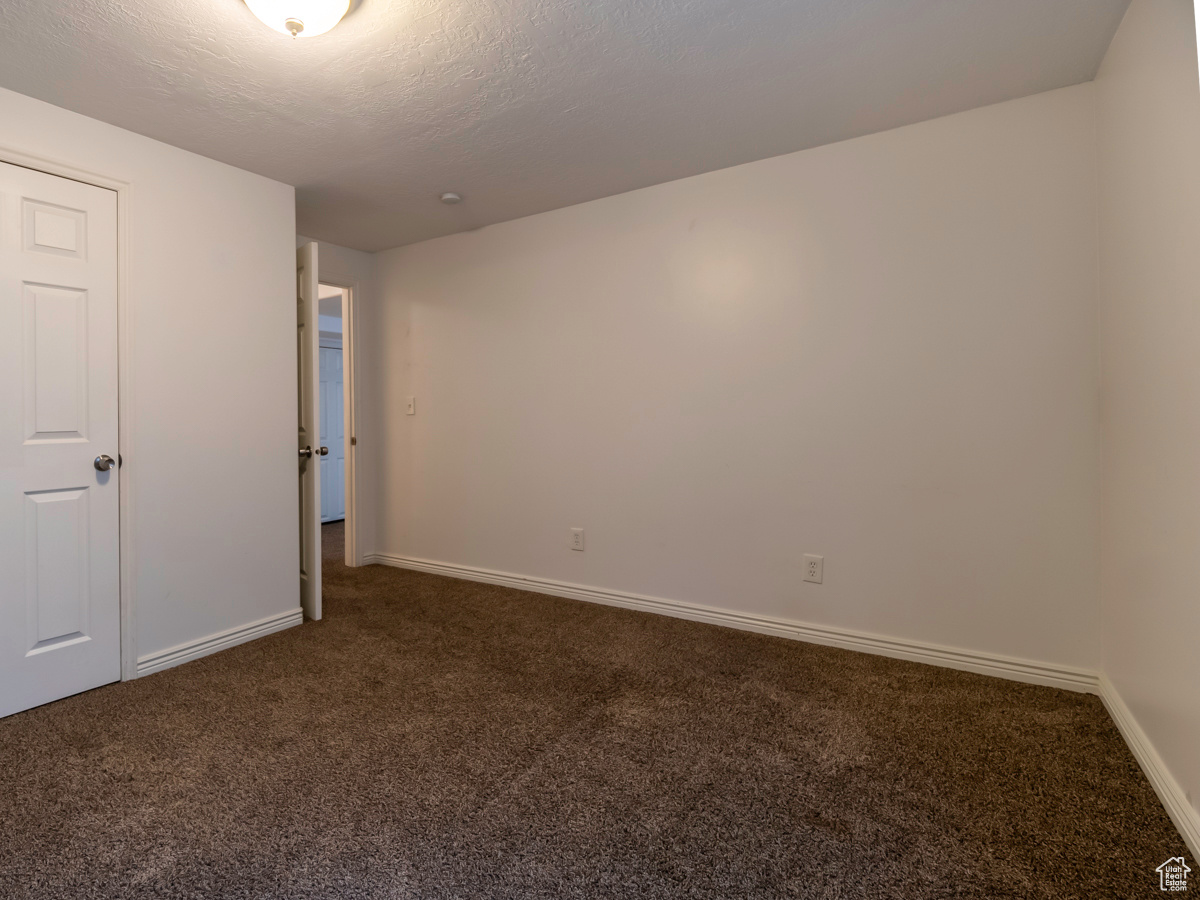 Unfurnished bedroom featuring dark carpet