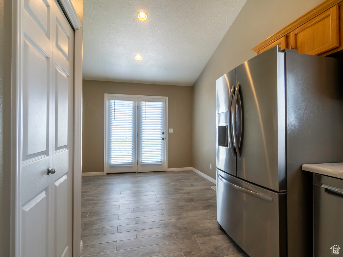 Kitchen with stainless steel appliances, hardwood / wood-style flooring, and lofted ceiling