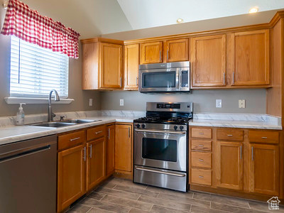 Kitchen featuring sink, lofted ceiling, and stainless steel appliances