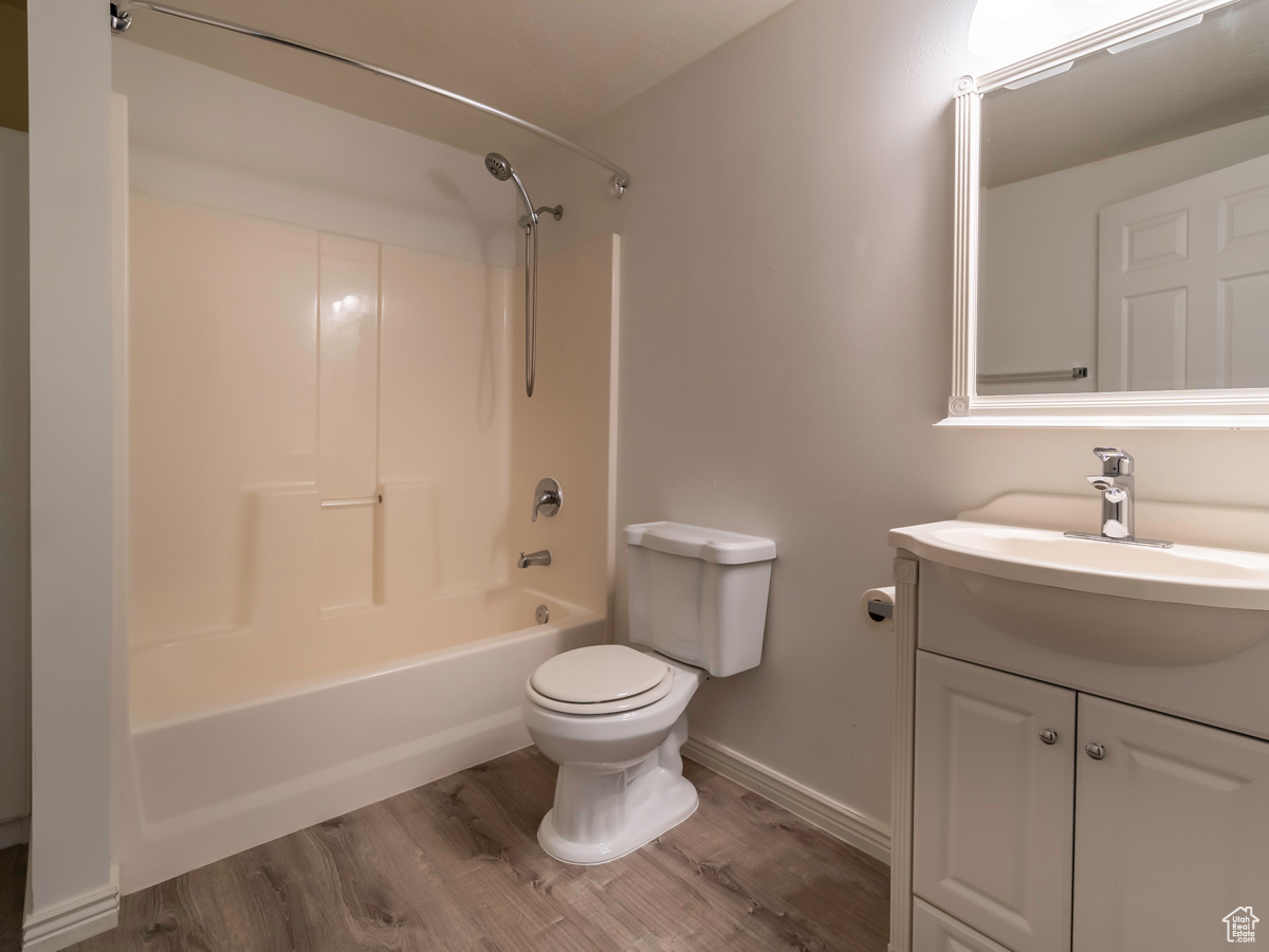 Full bathroom with toilet, bathing tub / shower combination, vanity, and hardwood / wood-style flooring