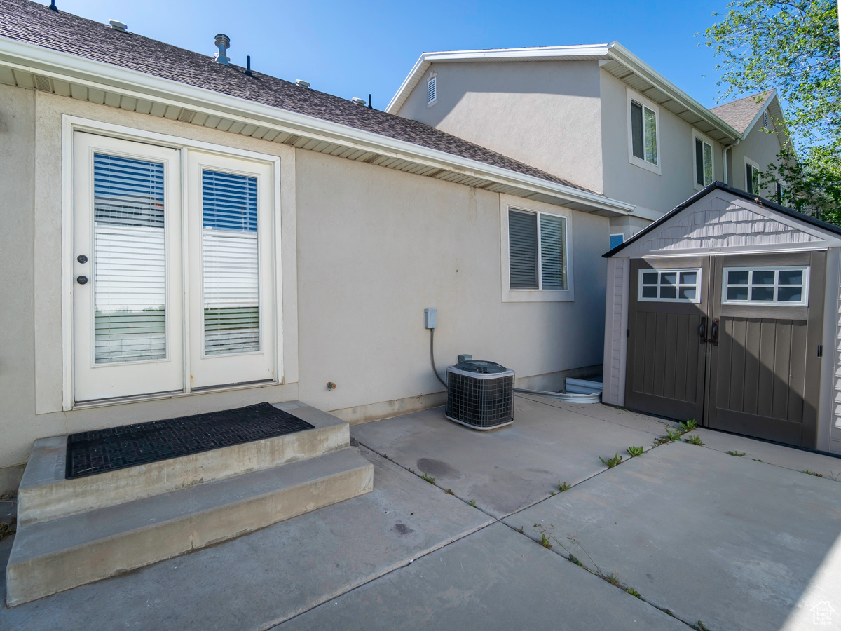 Rear view of property with a storage shed, central AC unit, and a patio area