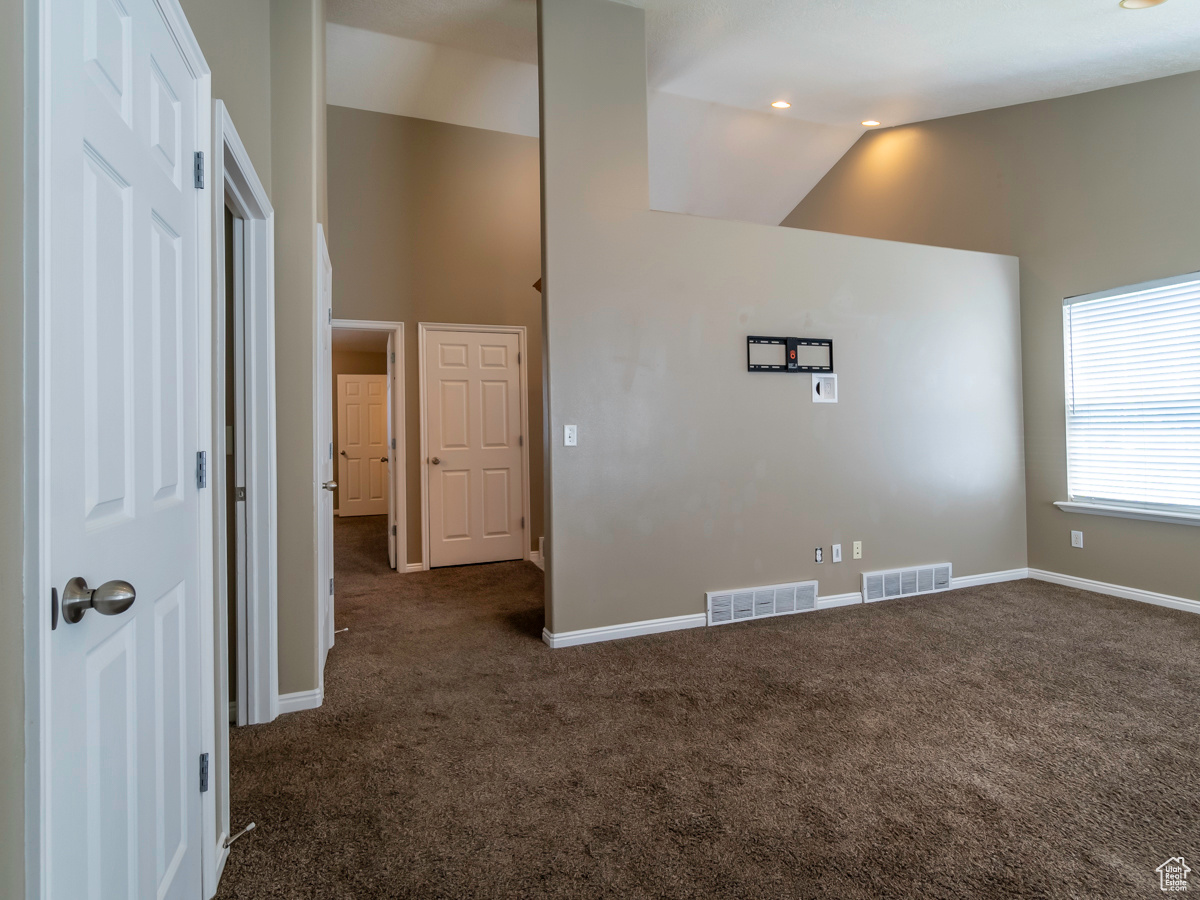 Spare room featuring lofted ceiling and dark carpet