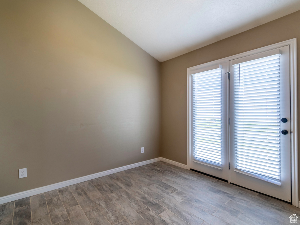 Empty room with vaulted ceiling, hardwood / wood-style floors, and plenty of natural light