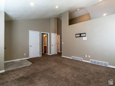 Carpeted empty room with high vaulted ceiling