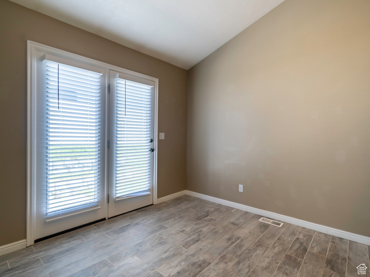 Unfurnished room featuring vaulted ceiling and hardwood / wood-style floors