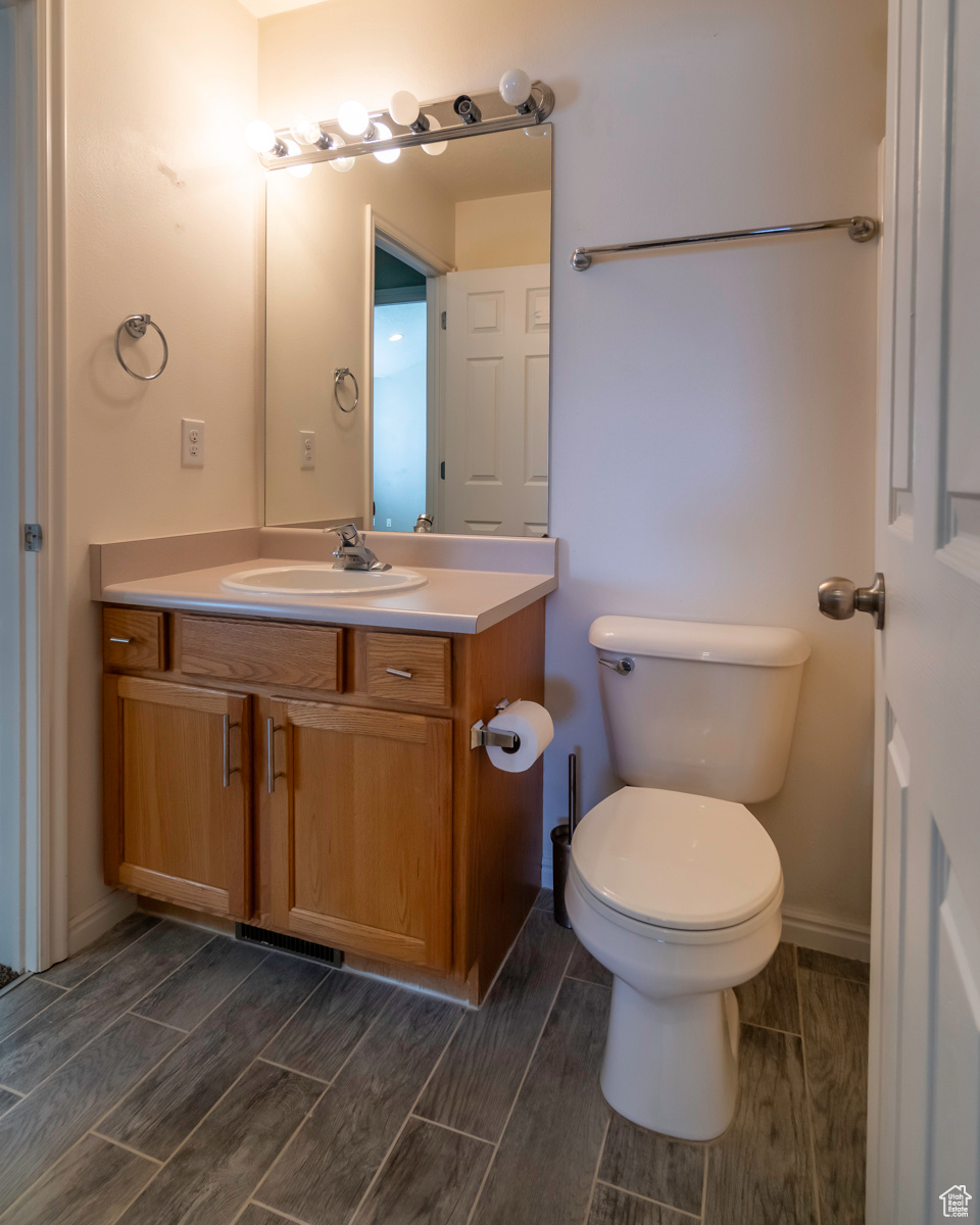 Bathroom with hardwood / wood-style floors, toilet, and vanity