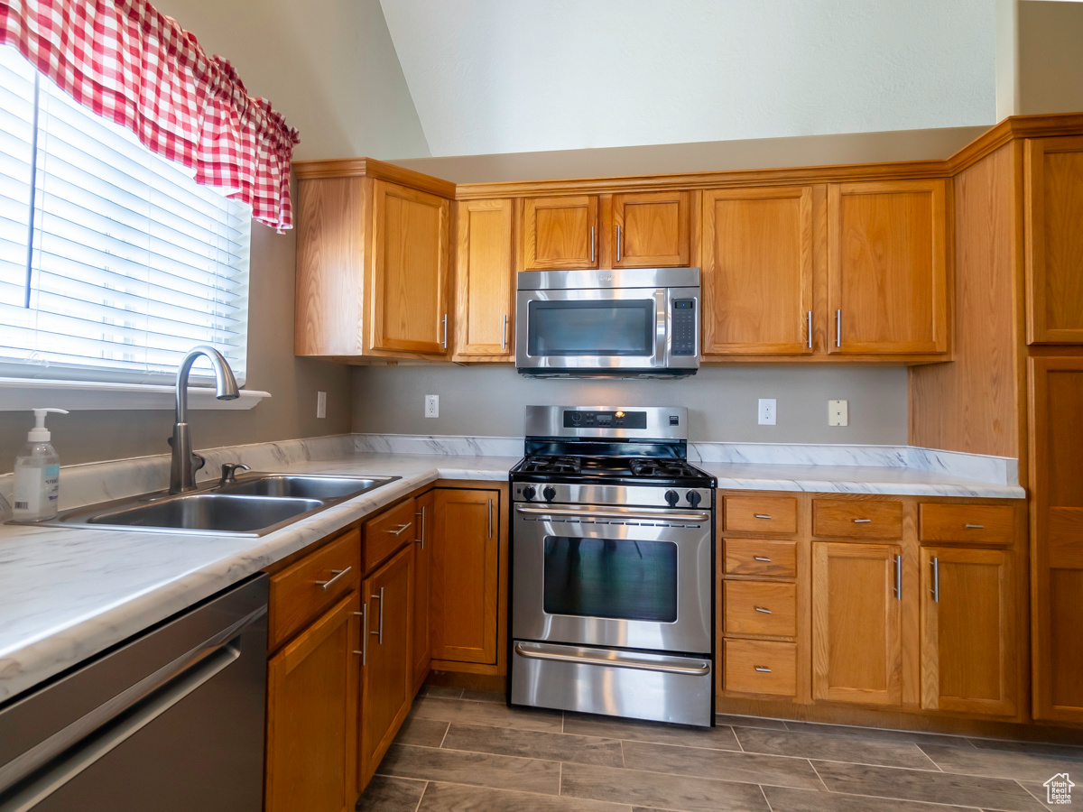 Kitchen featuring stainless steel appliances, sink, and lofted ceiling