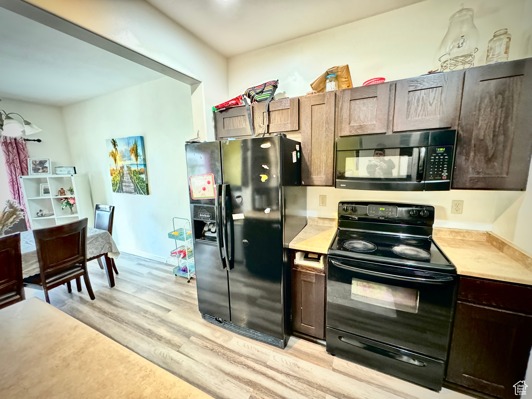 Kitchen featuring black appliances, light wood-type flooring, and dark brown cabinets