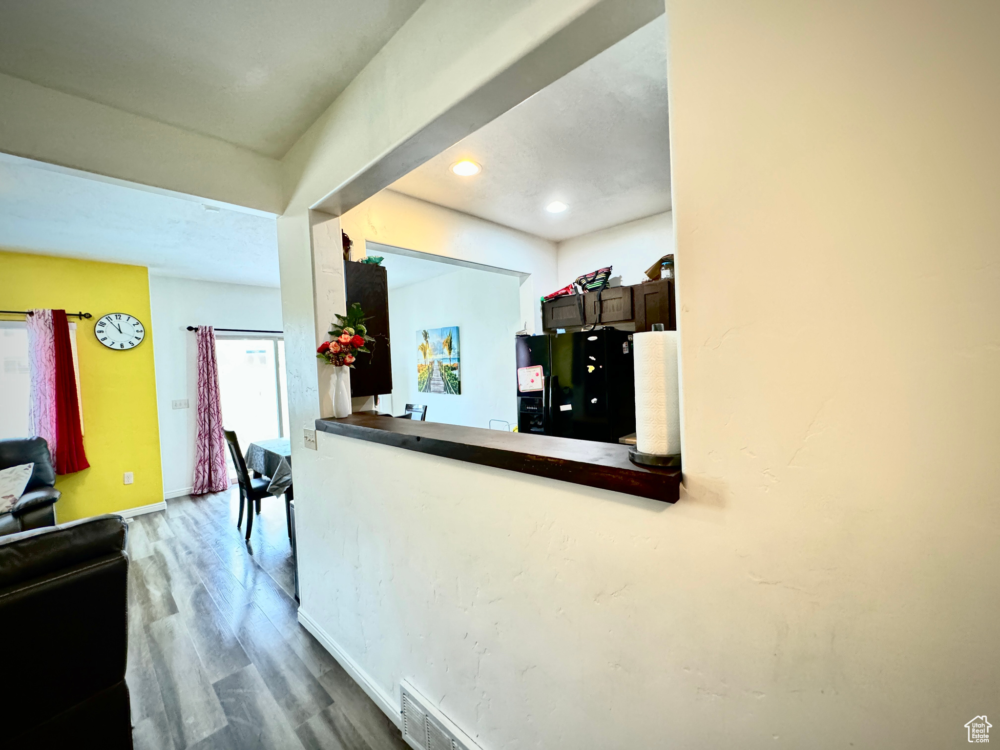 Kitchen with black fridge, dark brown cabinets, and wood-type flooring