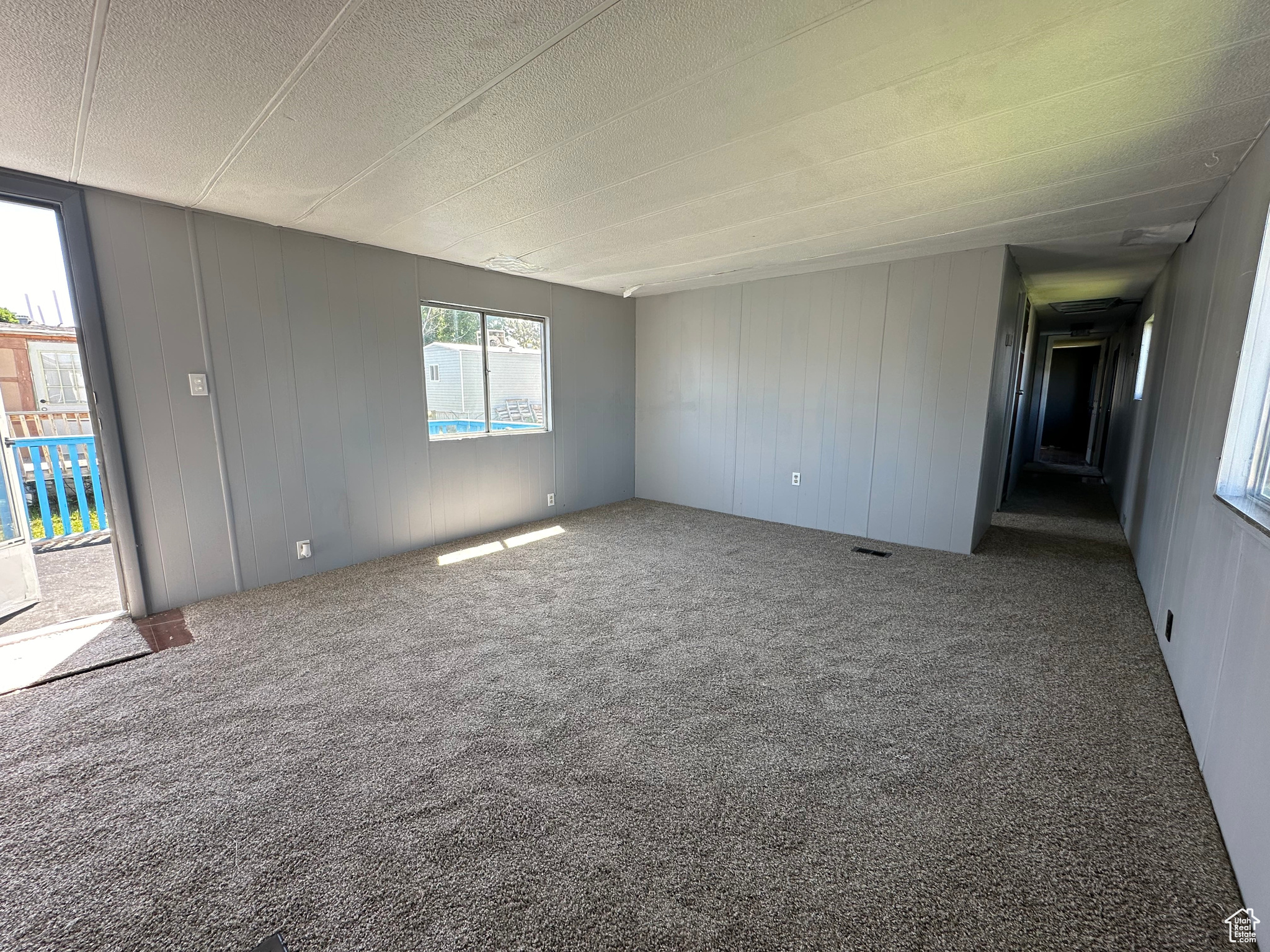 Unfurnished room with a textured ceiling, carpet flooring, and plenty of natural light