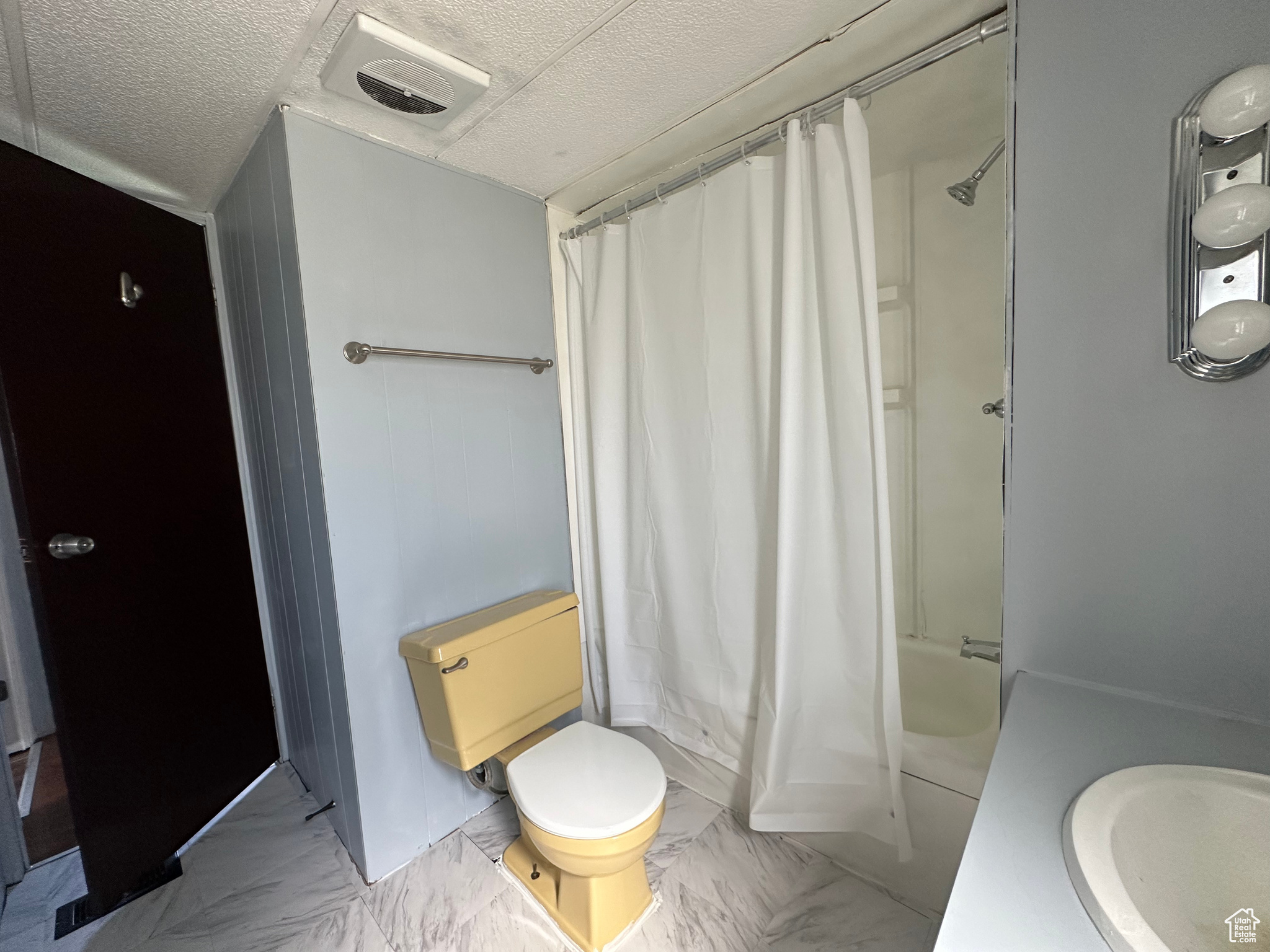 Full bathroom with a textured ceiling, tile floors, shower / tub combo with curtain, sink, and toilet