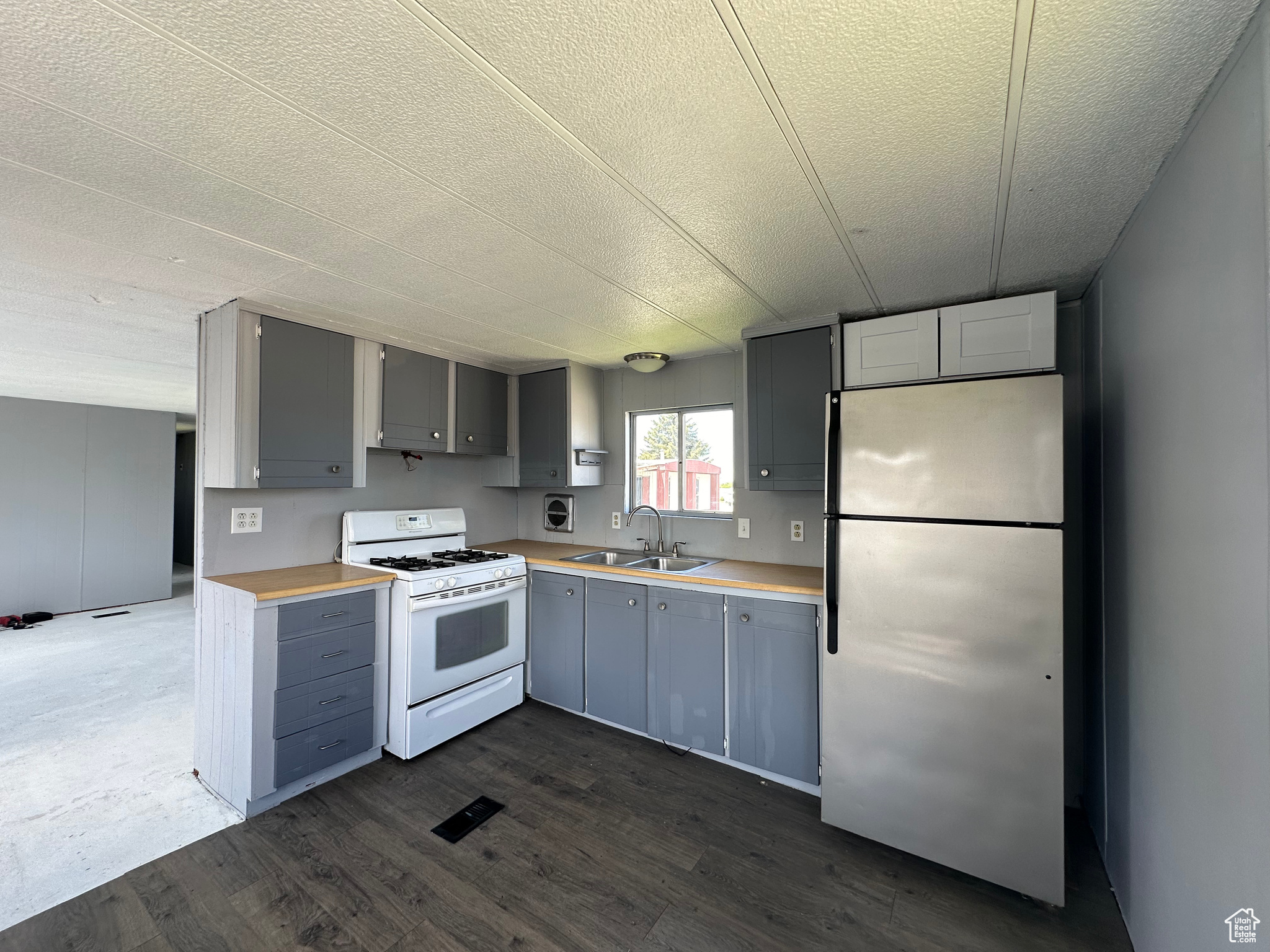 Kitchen featuring stainless steel refrigerator, white gas stove, dark hardwood / wood-style floors, gray cabinets, and sink