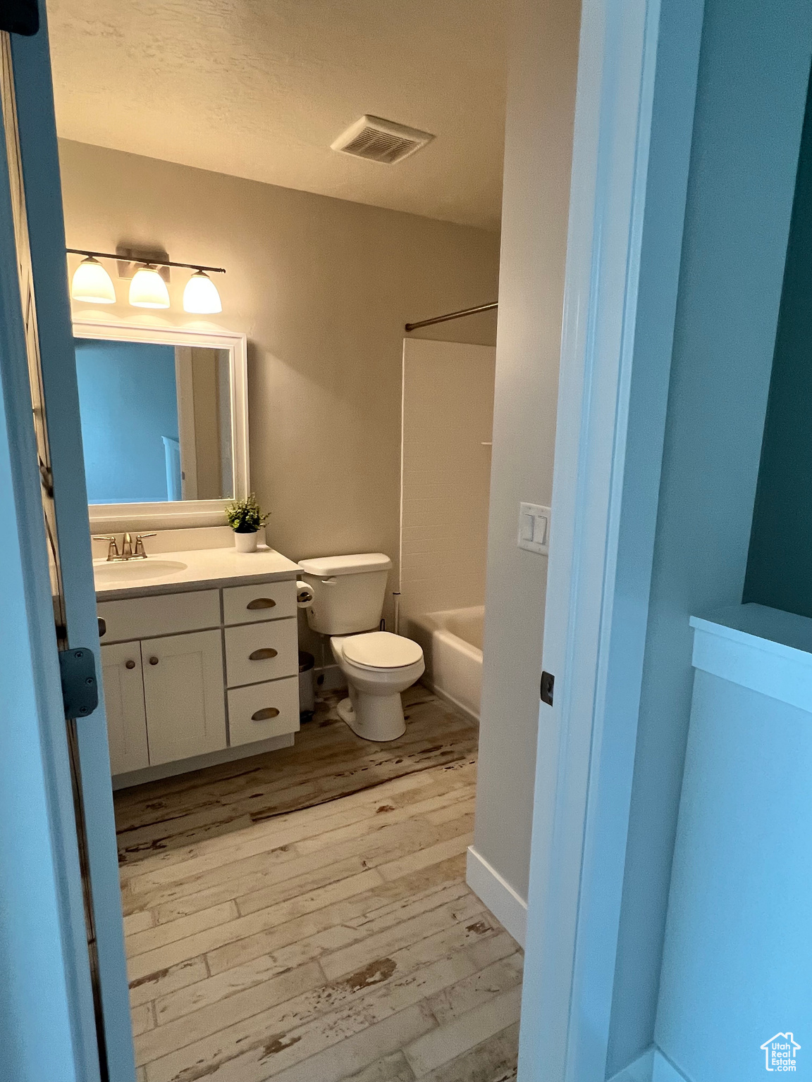 Full bathroom with shower / bathtub combination, hardwood / wood-style flooring, vanity, and toilet