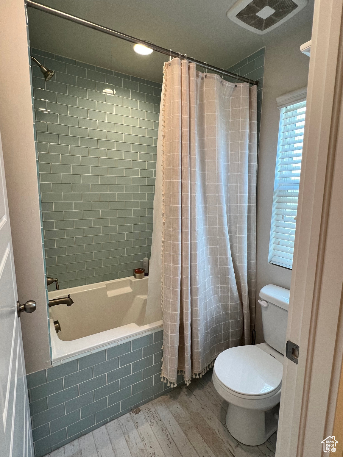 Main bathroom with shower / bath combination with curtain, hardwood / wood-style flooring, and toilet