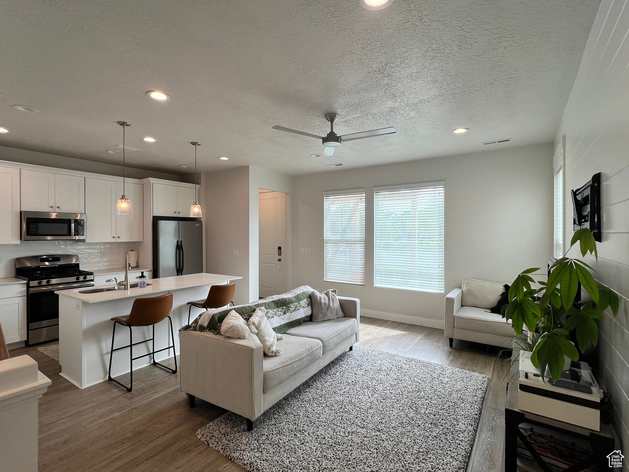 Living room with a textured ceiling, ceiling fan, hardwood / wood-style floors, and sink