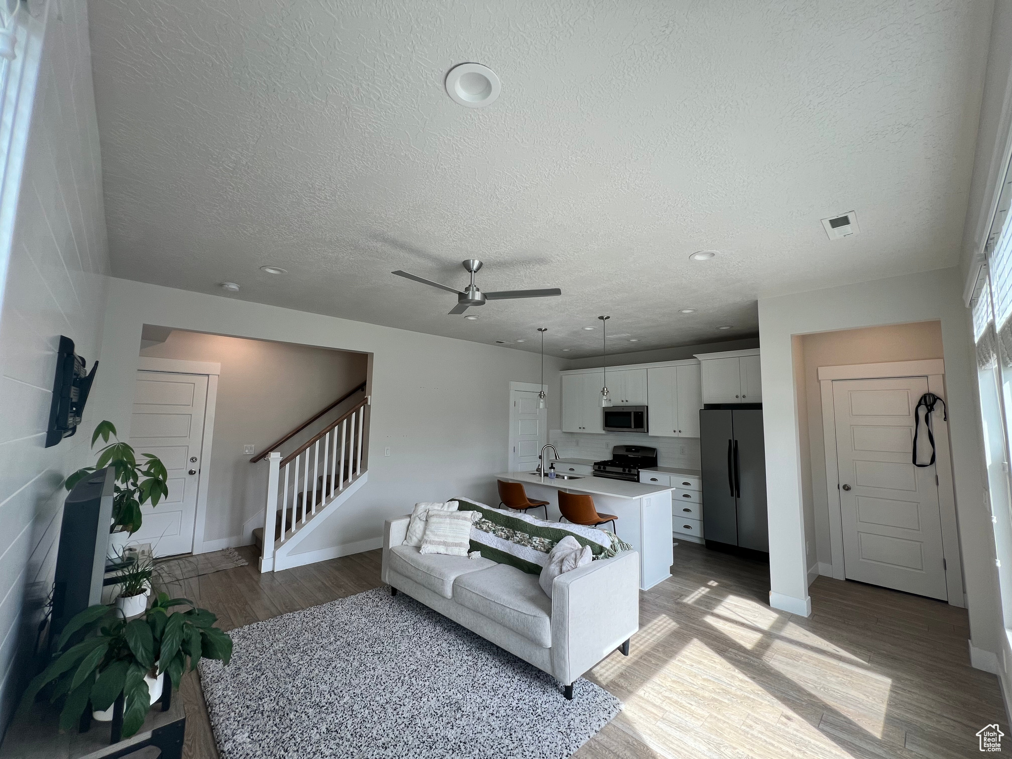 Living room featuring ceiling fan, sink, light hardwood / wood-style floors, and a textured ceiling