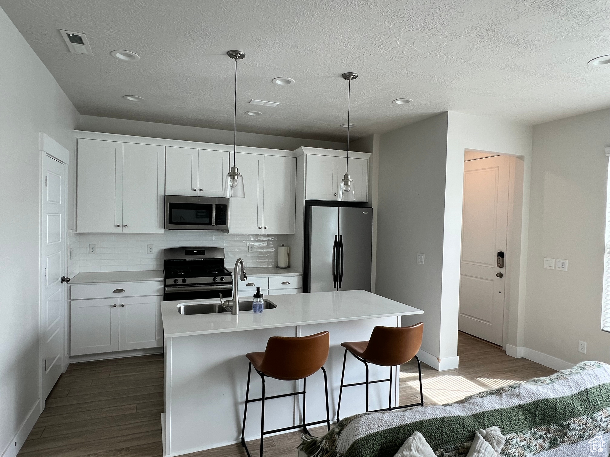 Kitchen with stainless steel appliances, wood-type flooring, and white cabinets