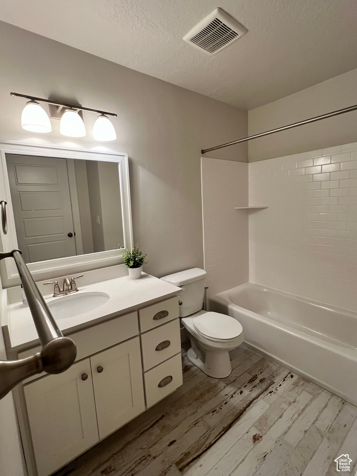 Full bathroom featuring a tiled shower / bath, hardwood / wood-style floors, vanity, and toilet