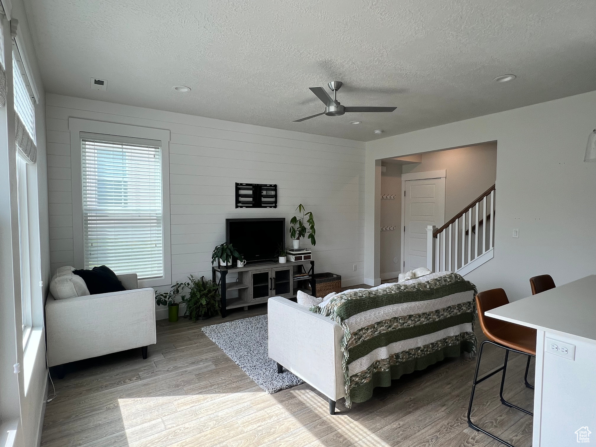 Living room featuring ceiling fan, hardwood / wood-style flooring, and a textured ceiling